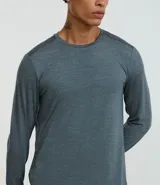 Remera deportiva de manga larga para hombre, color gris azulado jaspeado, con cuello redondo y costuras visibles en hombros y cuello.