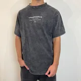Remera gris con efecto lavado, corte oversize y estampado en la espalda con texto y dibujo de una caracola.