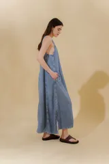 Vestido largo de jean celeste con breteles anchos, corte recto, abertura lateral y bolsillo plaqué en el pecho.
