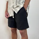 Bermuda negra de lino con corte arriba de la rodilla y cordón ajustable en la cintura.