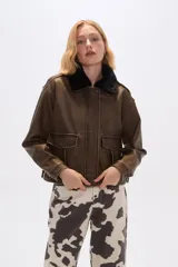Campera marrón de eco-cuero con cuello de piel sintética negra, cierre frontal con botones a presión, bolsillos con solapa en el pecho y corte holgado.