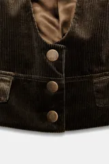 Chaleco marrón de pana con escote en pico, sin mangas, bolsillos delanteros y cierre con botones.