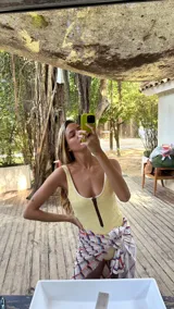 Traje de baño enterizo amarillo con textura arrugada, breteles finos y cierre marrón en el frente.