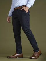 Pantalón de vestir azul marino, de corte slim fit, con bolsillos laterales y traseros. Se ajusta a la cintura con cinturón de cuero marrón.