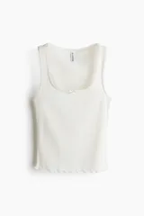Musculosa blanca de punto pointelle suave, corte ajustado, con escote cuadrado, moño de satén y bajo sobrehilado.