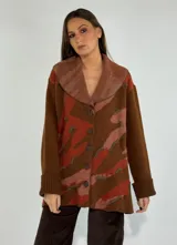 Saco marrón con diseño abstracto en tonos naranja y beige, con cuello solapa y cierre frontal con botones.