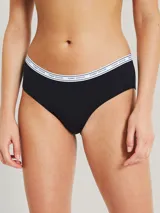 Bombacha hipster negra de algodón y elastano, con cintura elástica blanca con logo Tommy Hilfiger repetido.