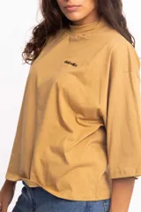 Remera blanca de corte cuadrado con cuello subido y mangas 3/4 amplias.