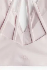 Top deportivo color rosa claro, de sujeción suave, confeccionado en tejido funcional con tecnología SoftMove™ y DryMove™. Tiene breteles finos cruzados en la espalda y copas forradas con relleno extraíble.
