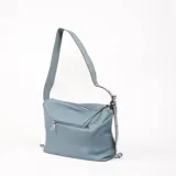 Bolso bandolera de cuero sintético color celeste, con textura granulada y correa ancha con ojales metálicos.