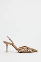 Zapato destalonado color beige con puntera fina, confeccionado en mesh con abalorios y tira trasera elástica. Tacón fino de 8 cm.