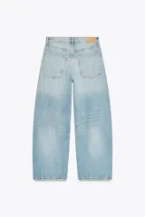 Pantalón de jean azul oscuro, tiro medio, corte amplio tipo baggy balloon con costuras torcidas y cinco bolsillos. Cierre frontal con cremallera y botón metálico.