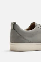 Zapatillas urbanas grises de caña baja, con cordones, puntera redondeada, forro interior en contraste y suela con ligera textura.