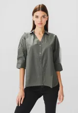 Camisa verde militar de algodón, corte holgado, con cuello camisero, cierre frontal con botones y mangas 3/4 con puños.