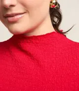 Blusa roja de poliéster texturizado con cuello alto y mangas cortas.