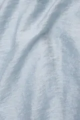 Vestido largo hasta el tobillo color celeste, de tejido arrugado liviano, con escote recto y breteles finos. Presenta lazos en los costados, forro hasta arriba de las rodillas y caída posterior más larga.