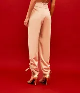 Pantalón jogger color beige de satín, con cintura elástica y lazos ajustables en los tobillos.