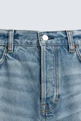 Jeans de denim de algodón, tiro medio, con pierna recta y ajuste relajado. Presentan un efecto lavado claro y cierre frontal con botones.