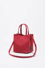 Bolso de mano pequeño tipo tote bag, color rojo, confeccionado en gabardina con detalles en piel. Posee asas de mano y correa ajustable para llevar al hombro o cruzado. Lleva placa metálica con el logo de la marca en el frente.