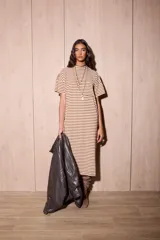 Vestido largo de algodón, color blanco hueso, con rayas horizontales marrones. Presenta cuello redondo, mangas cortas y corte recto.