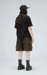 Bermuda cargo unisex con bolsillos laterales con tapa, corte oversize y proceso de desgaste. Confeccionada en rústico de algodón color negro con efecto degradado.