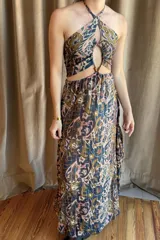 Vestido largo con estampado paisley en tonos tierra y azules, con top halter y cut-outs laterales. La falda es holgada y tiene elástico en la cintura.