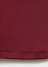 Camiseta sin mangas color borgoña, de tejido elástico y diseño entallado, con cuello redondo y tirantes anchos.