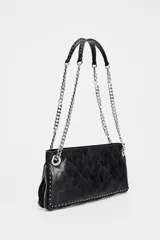Bolso alargado negro con tachas plateadas en el borde inferior y detalle de cremallera en el corte. Tiene asa de cadena plateada multiposición para usar al hombro o como bandolera. Incluye bolsillo interior con cremallera y cierre principal con cremallera.