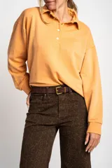 Sweater color naranja con cuello polo y botones, de corte holgado y mangas largas.