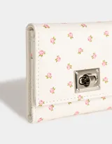 Billetera de cuerina color crema con estampado de pequeñas rosas rosadas, con broche metálico plateado y compartimentos para tarjetas.