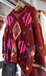 Sweater tejido a mano en lana color borgoña, con diseño geométrico multicolor en intarsia y bordado.