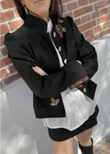 Chaqueta negra de paño de lana y cashmere, con cuello Mao, botones dorados, puños con tajo y bordado a mano, y forro interior de seda estampada.
