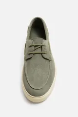 Zapato náutico de cuero color azul marino con cordones finos y suela plana.