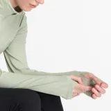 Buzo deportivo verde claro de New Balance, con cierre de un cuarto en el cuello, mangas largas con orificios para los pulgares y logo estampado en el pecho.