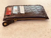 Billetera tarjetero de cuero con cierre y espacio para billetes y monedas.