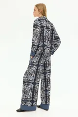 Pantalón de lino liviano con estampado paisley en tonos azul y blanco. Modelo de corte holgado con cintura elástica de tiro alto, bolsillos laterales discretos y piernas amplias.