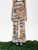 Pantalón de jean azul oscuro con corte acampanado, tiro medio y dobladillo en el ruedo. Presenta costuras marcadas en el frente y estampado abstracto en tonos grises y blancos en el interior del dobladillo.