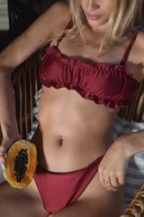 Conjunto de bikini color borgoña, compuesto por un corpiño con volados y tirantes finos, y una bombacha clásica.