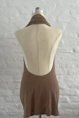 Vestido corto color beige, con escote halter y espalda descubierta. Ajustado al cuerpo y confeccionado en microtul.