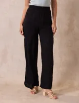 Pantalón negro de rayón con bordados florales, pretina ancha elastizada en punto smock y corte palazzo. Marca Liv Los Angeles.