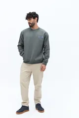 Buzo de algodón color beige claro, con cuello redondo y puños. Presenta un estampado grande en la espalda con texto en gris y blanco, incluyendo referencias a 'London', 'Southbank Art Gallery Centre' y una representación estilizada de la bandera del Reino Unido.