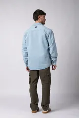 Chaqueta de jean celeste de corte recto, con cuello clásico, cierre frontal con botones metálicos y bolsillo de parche en el pecho.