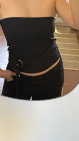 Top negro sin mangas, con escote recto y argolla metálica en la cintura.