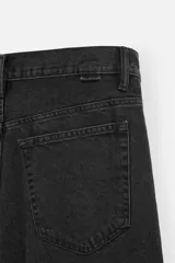Bermuda de jean color negro, corte amplio, con cinco bolsillos, efecto lavado y cierre frontal con cremallera y botón.