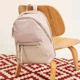 Mochila negra de tela impermeable con detalles en cuero sintético. Tiene un compartimento principal con cierre, un bolsillo frontal con cierre y un compartimento interno para notebook de 15 pulgadas.