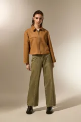 Campera cropped color camel de poliéster, con cuello camisero, cierre frontal y un bolsillo con cierre en el pecho. Está decorada con tachas plateadas distribuidas por toda la prenda.