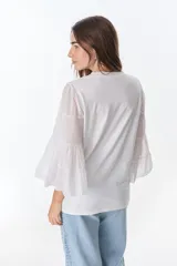 Blusa blanca de algodón con mangas largas acampanadas con volados.