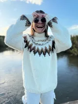 Sweater tejido a mano en lana merino color crema con diseño geométrico en marrón y beige en el cuello, pecho y puños.