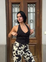 Chaleco negro con escote halter y cierre frontal con botones.