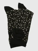 Calcetín de largo medio, color negro, con puño negro liso y estampado integral de pequeñas flores blancas y hojas verdes.